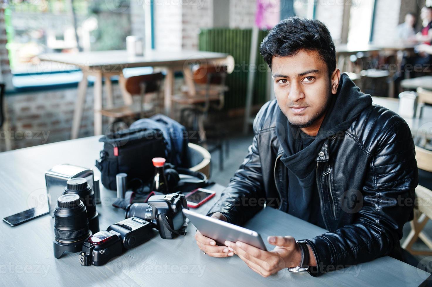 joven fotógrafo asiático inteligente que trabaja con una tableta mientras está sentado en el café. foto