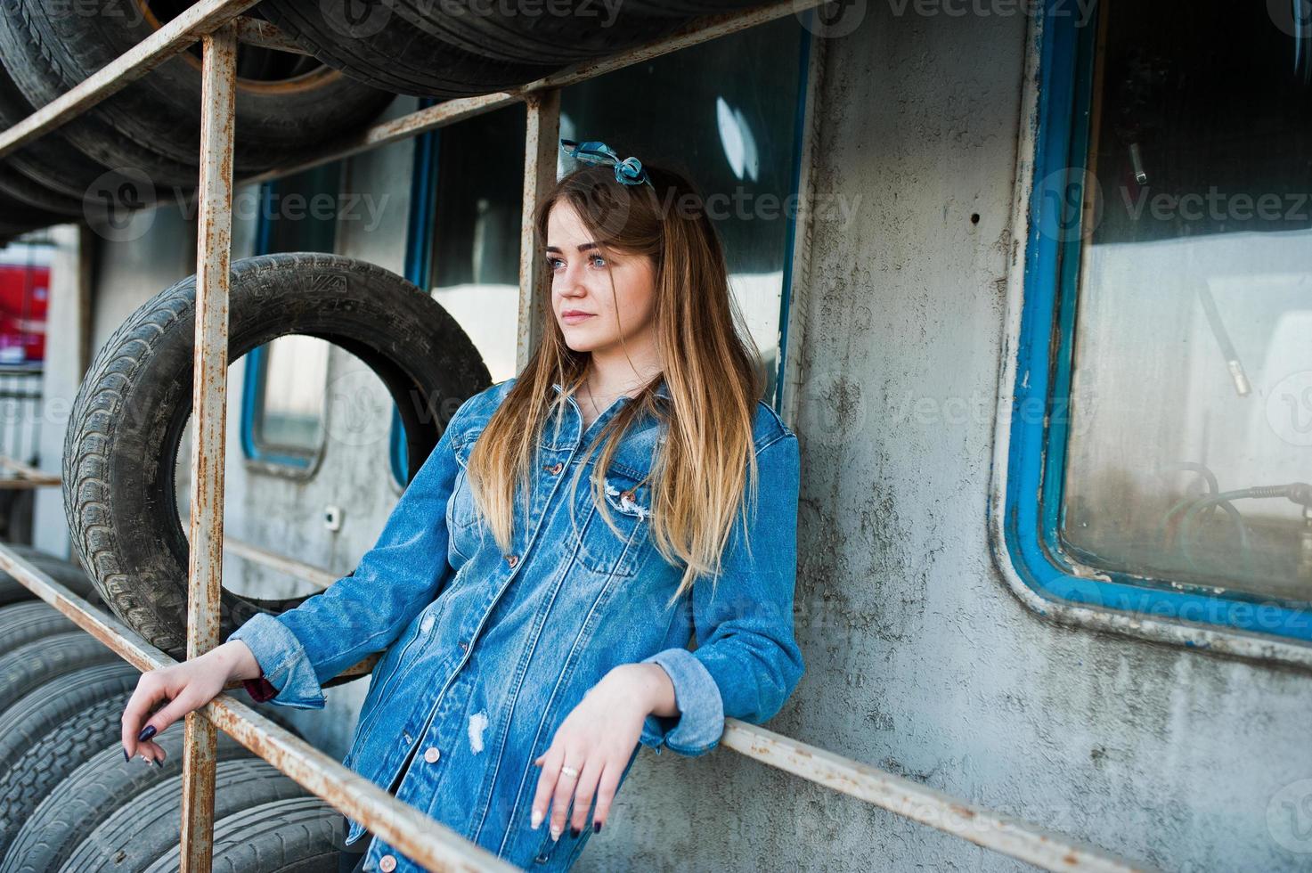 Young hipster girl in jeans jacket and head scarf at tire fitting zone. photo