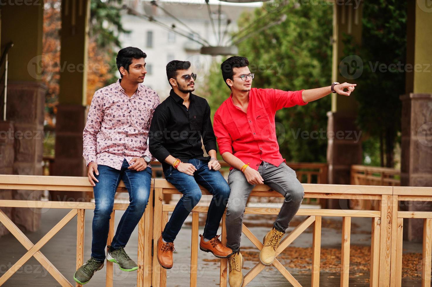 tres amigos estudiantes indios posaron en la calle, uno de los hombres muestra el dedo. foto