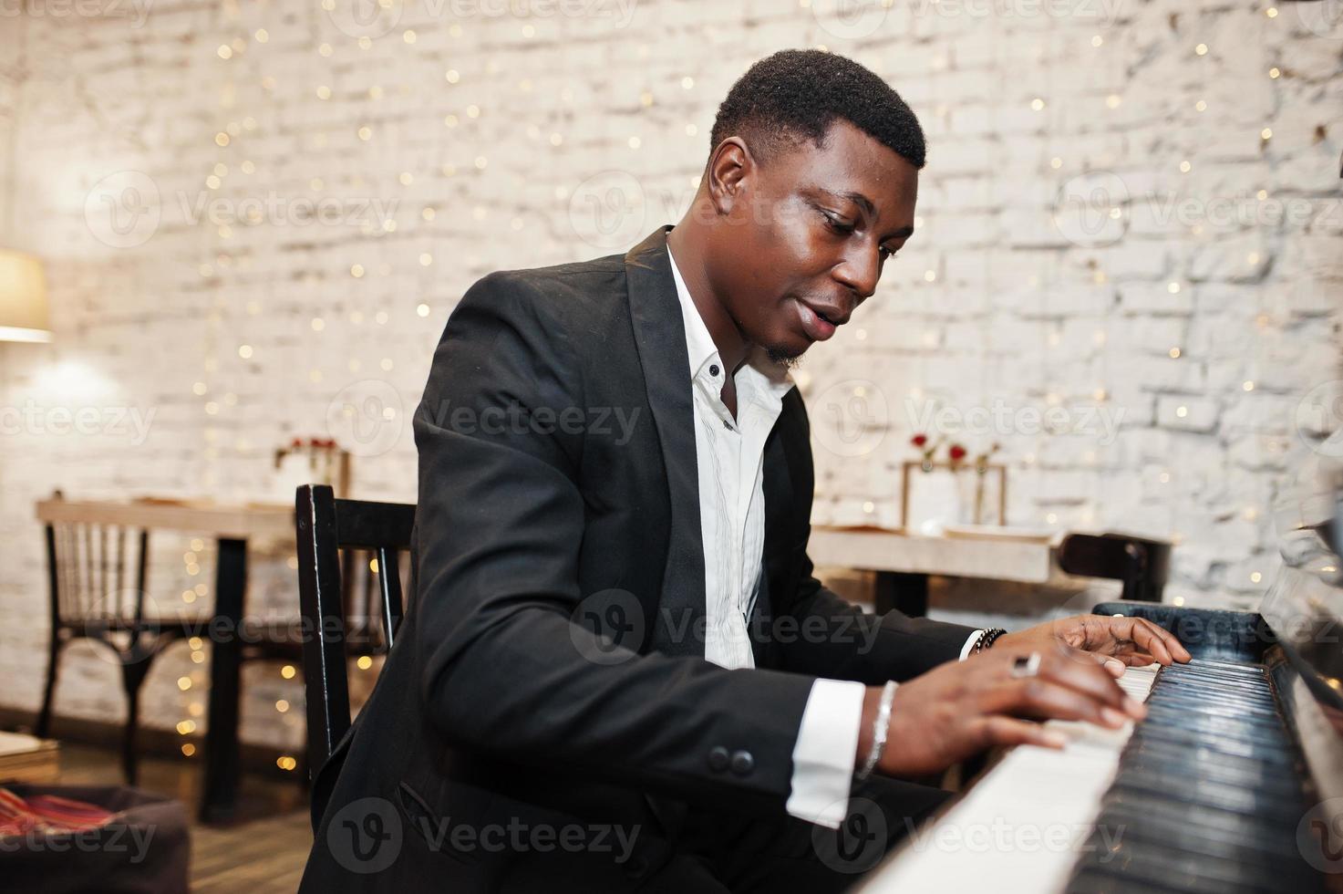 Strong powerful african american man in black suit play piano. photo