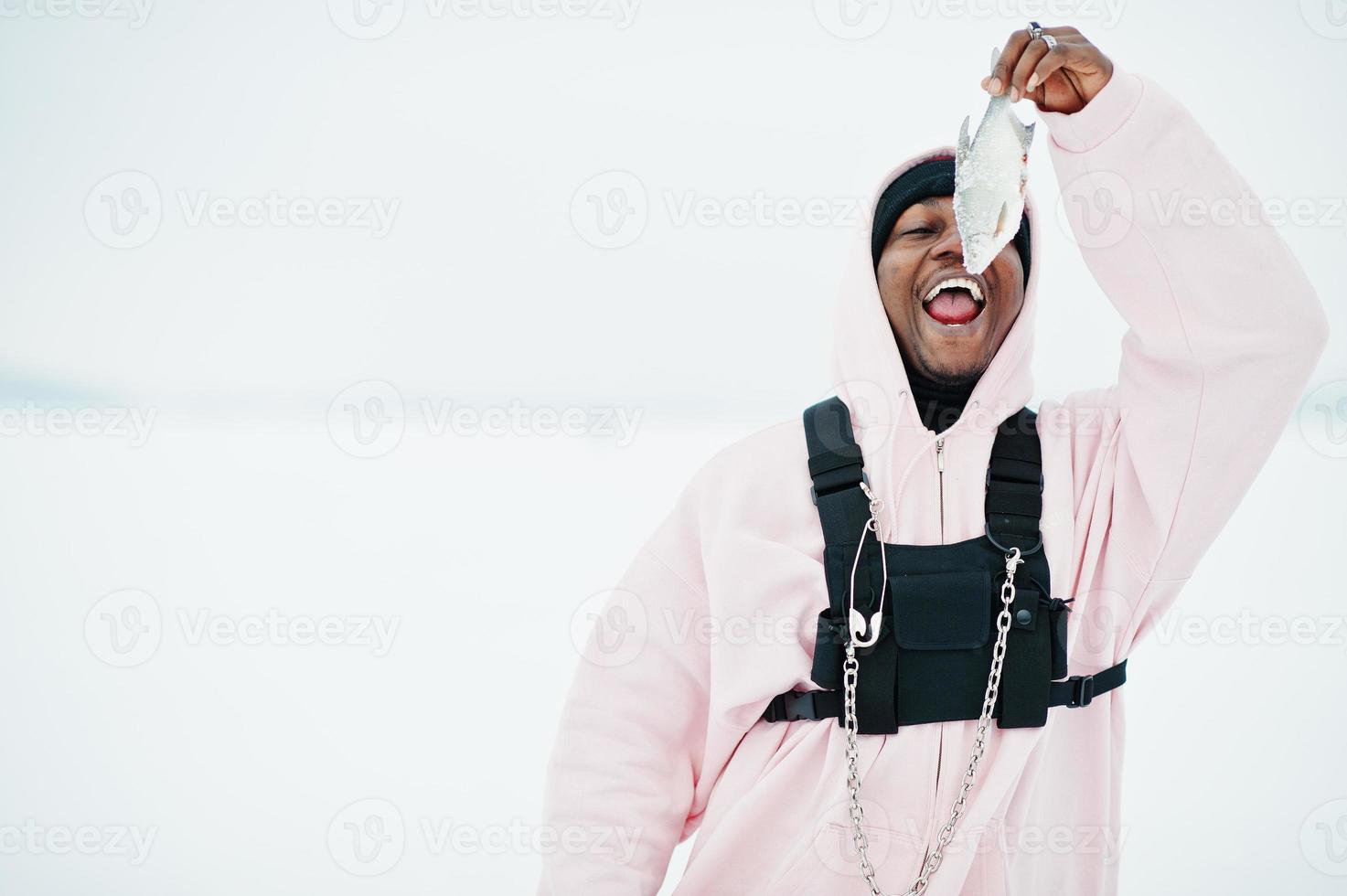 African american fisherman with fresh frozen fish at hand. Winter fishing. photo