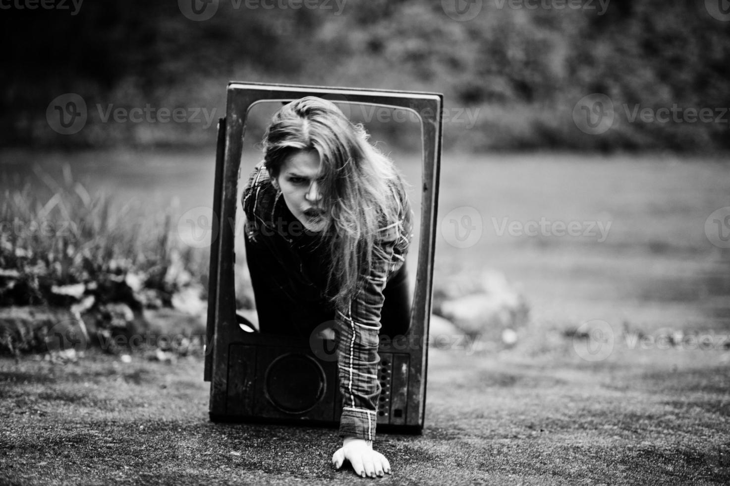 Fashion portrait of redhaired sexy girl outdoor. Model attractive dramatic woman with old tv box. photo