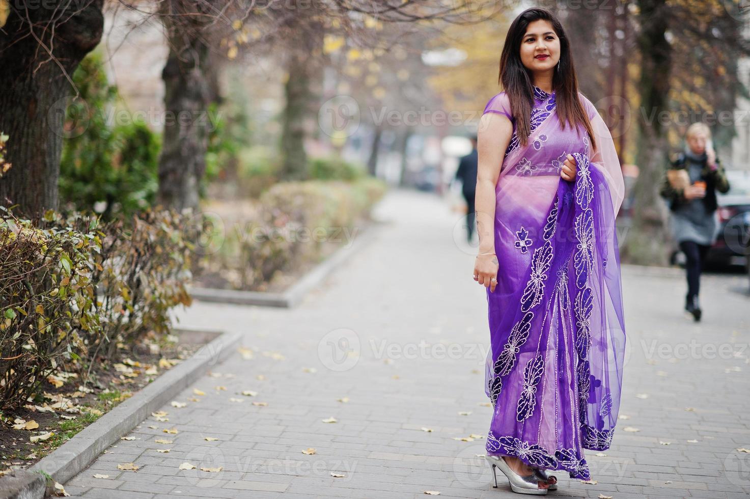 Indian hindu girl at traditional violet saree posed at autumn street. photo