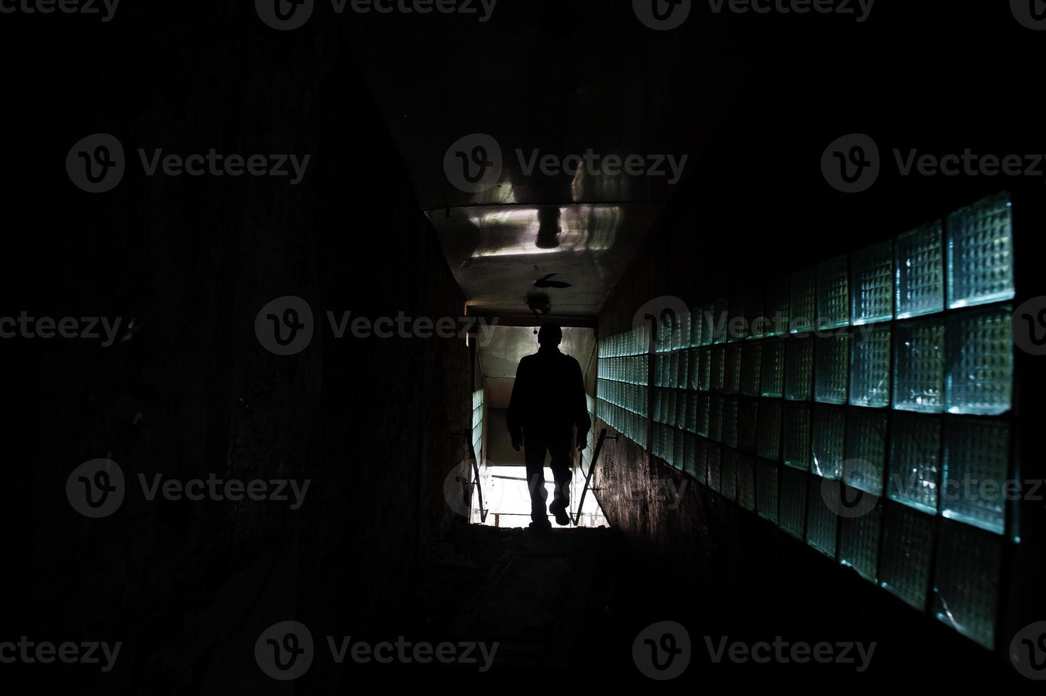 Industrial interior of an old abandoned factory. Man in shadow tonnel. Scary concept. photo