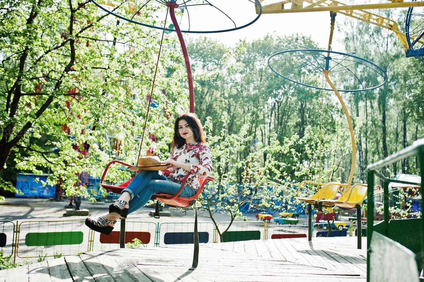 Portrait of brunette girl in pink glasses and hat with ice cream at amusement park. photo