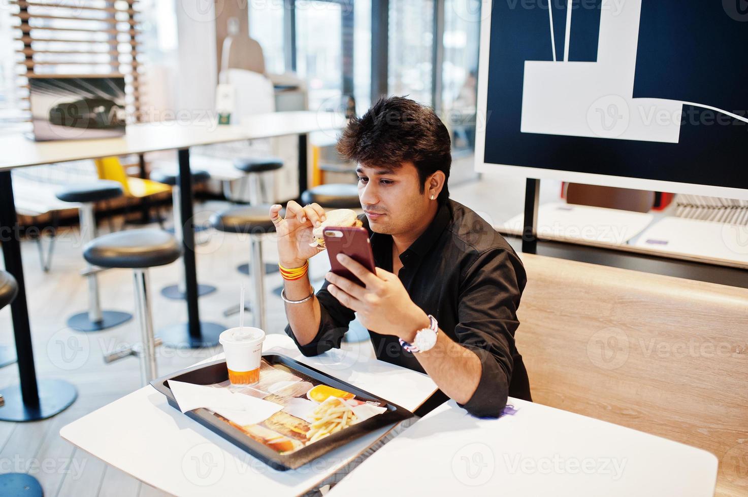 Stylish and funny indian man sitting at fast food cafe and eating hamburger and making selfie by phone. 10492417 Stock Photo at Vecteezy Stylish and funny indian man sitting at fast food cafe and eating hamburger and making selfie by phone. 10492417 Stock Photo at Vecteezy
