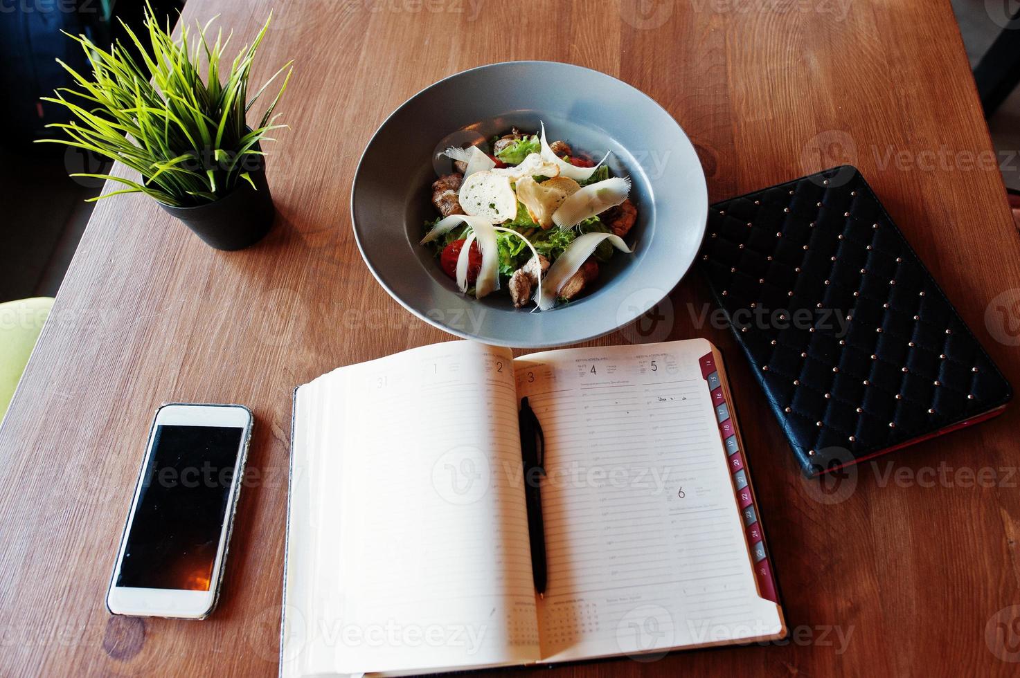 Table with phone notebook, tablet and plate with salad. photo