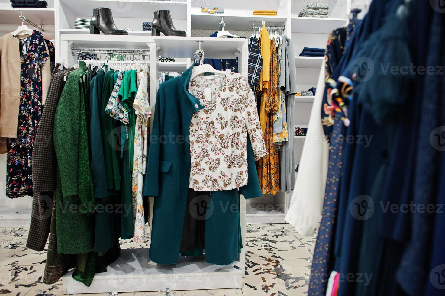 conjunto de ropa colorida femenina en los estantes con zapatos en la tienda de ropa nueva boutique moderna. foto