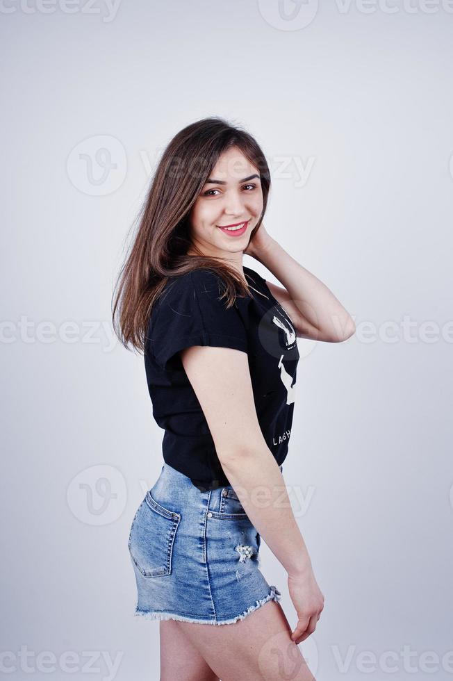 Portrait of an attractive girl in black t-shirt saying lol and denim shorts posing in the studio. photo