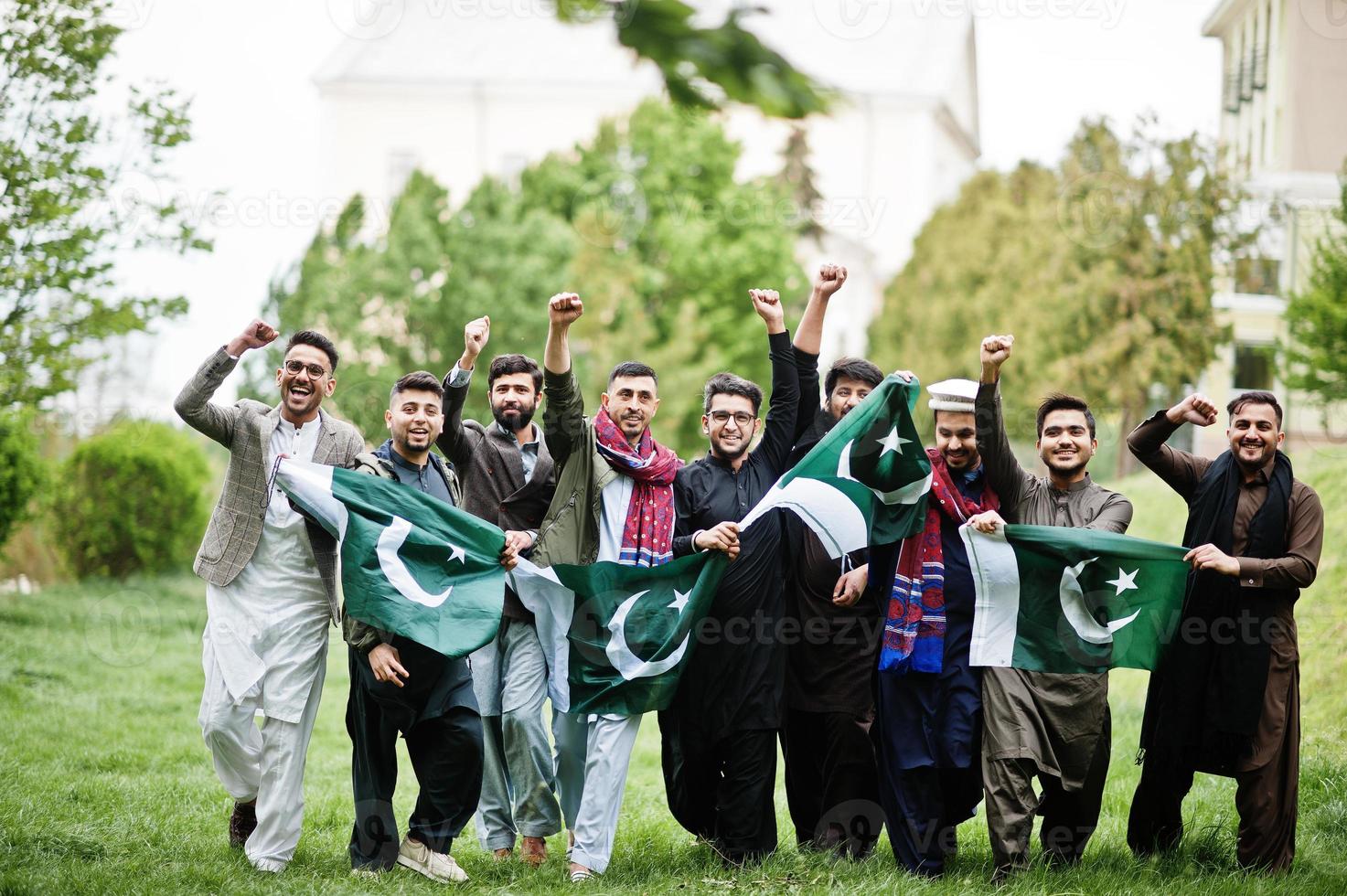 grupo de hombres paquistaníes vestidos con ropa tradicional salwar kameez o kurta con banderas de pakistán. foto