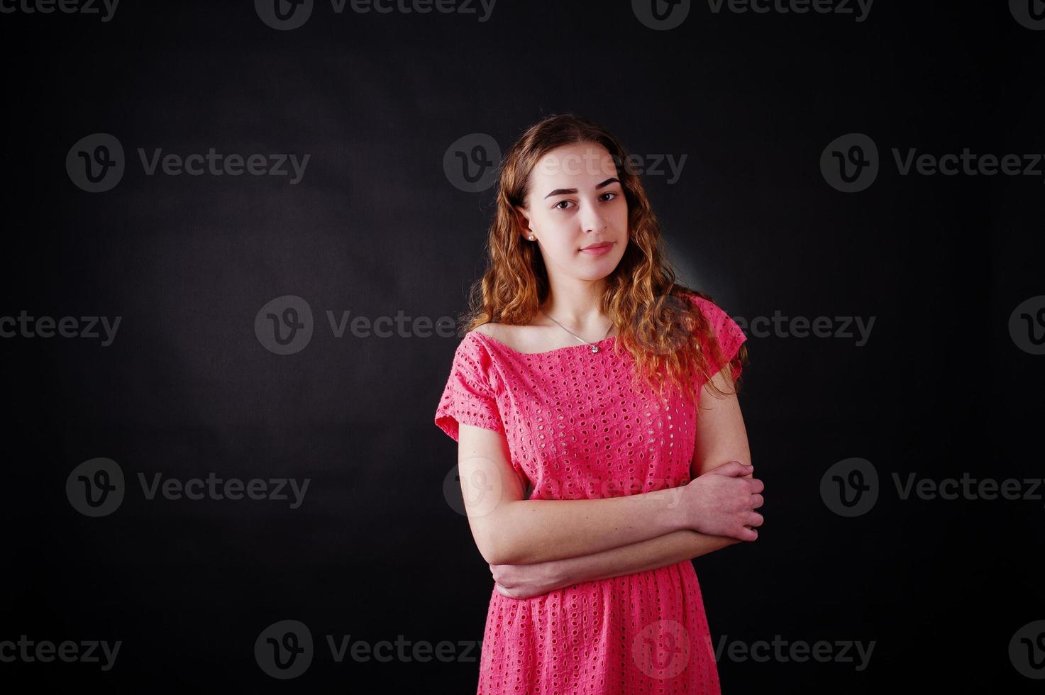 Young girl in red dress against black background on studio. photo