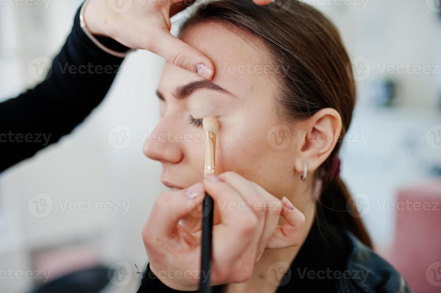 Make up artist work in her beauty visage studio salon. Woman applying by professional make up master. Beauty club concept. photo