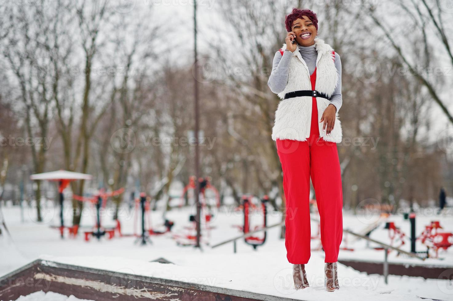 African american woman in red pants and white fur coat jacket