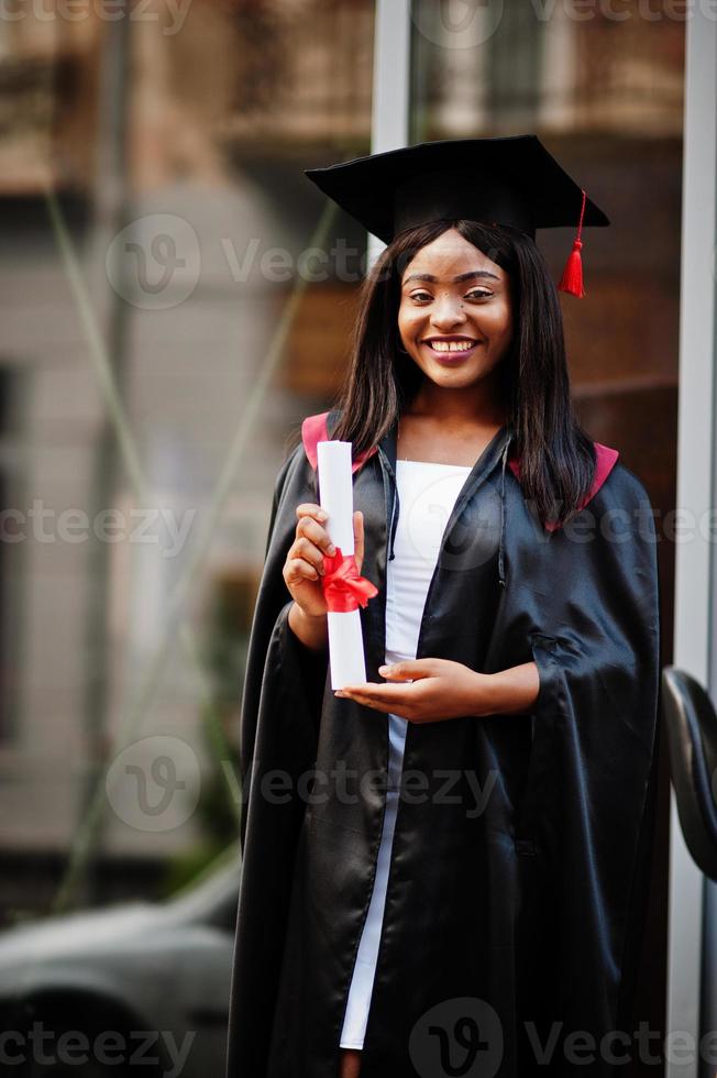 Young female african american student with diploma poses outdoors. photo