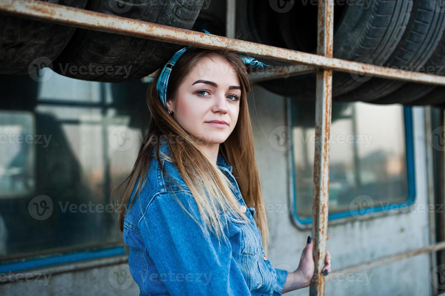 Young hipster girl in jeans jacket and head scarf at tire fitting zone. photo