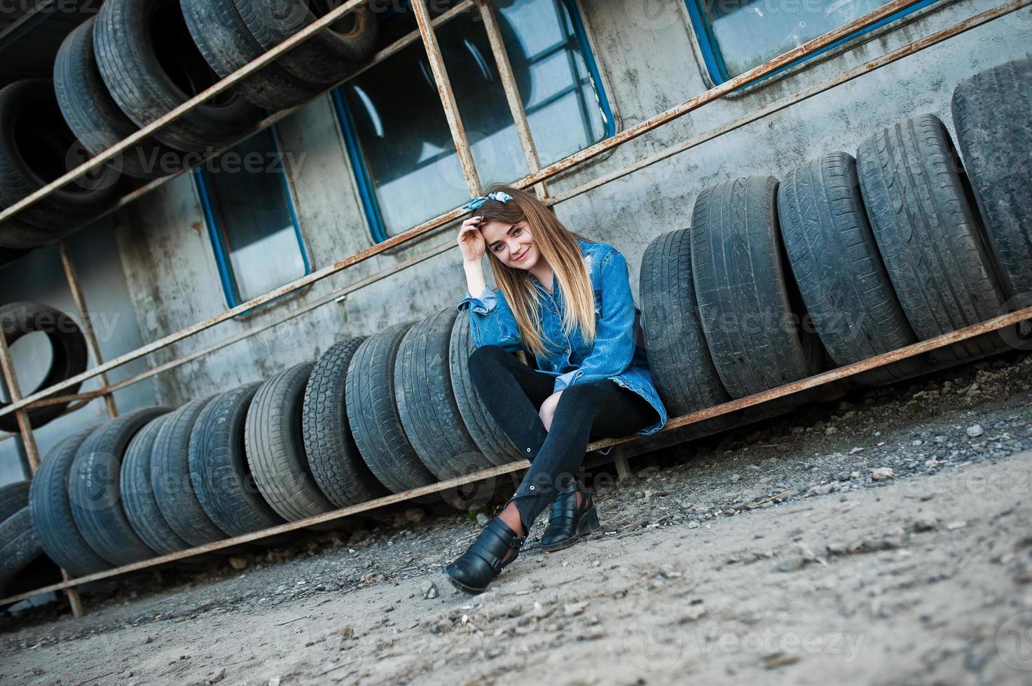 Young hipster girl in jeans jacket and head scarf at tire fitting zone. photo