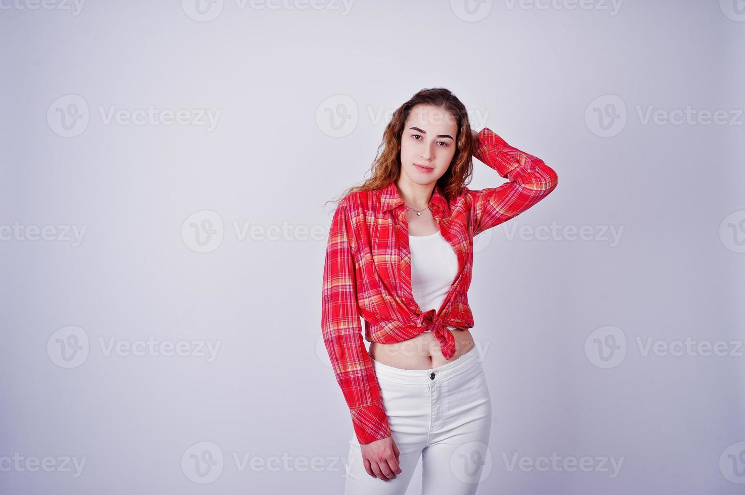 joven en camisa roja a cuadros y pantalón blanco sobre fondo blanco en el estudio. foto