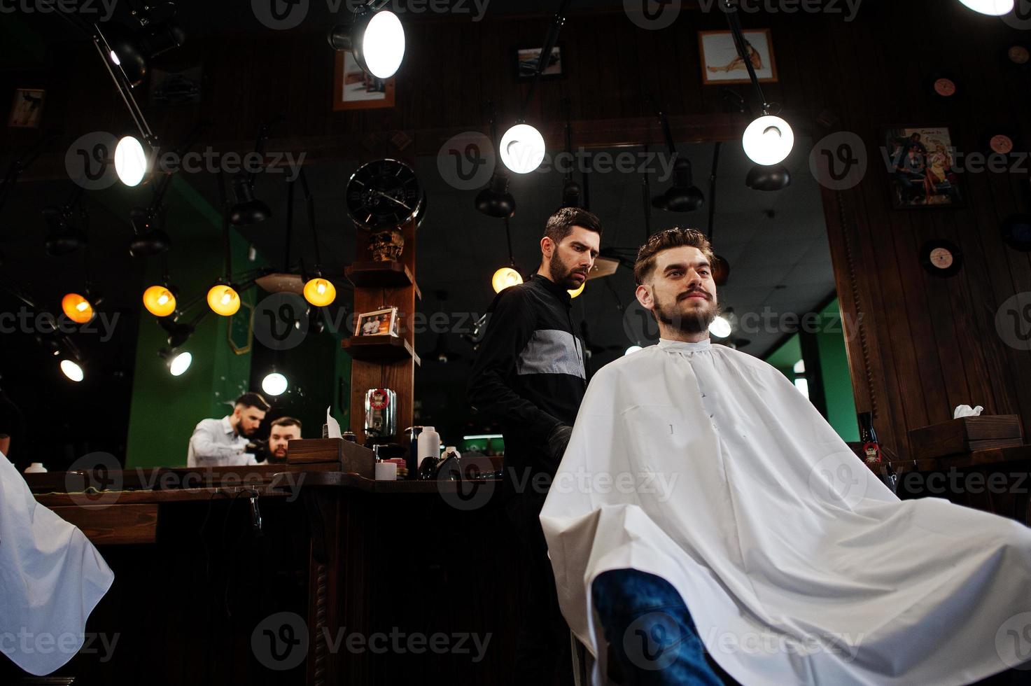 apuesto hombre barbudo en la barbería, peluquero en el trabajo. foto