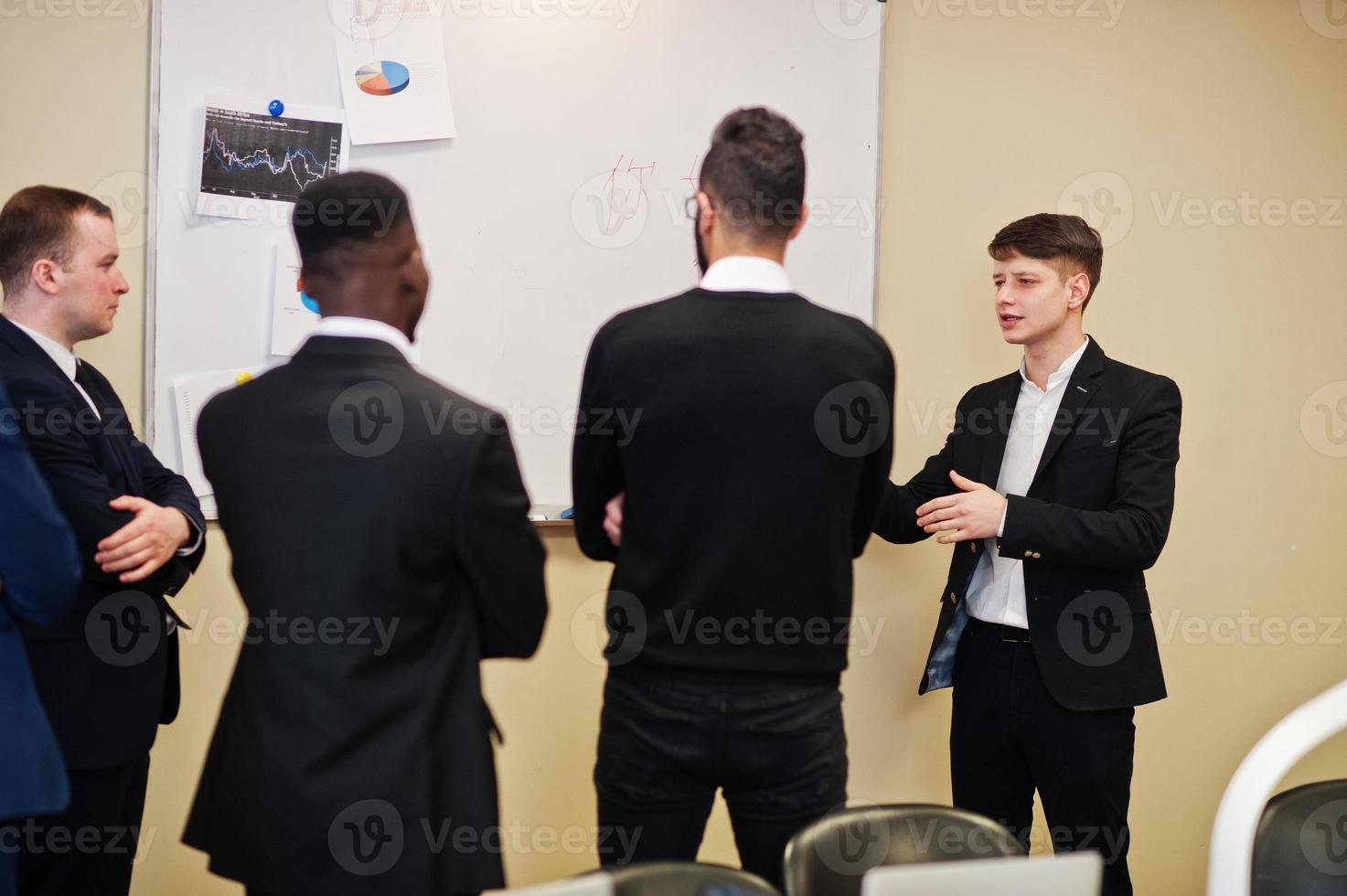 Male colleagues working in team cooperate , multiracial crew of employees concentrated on project planning against board and discussing ideas. photo