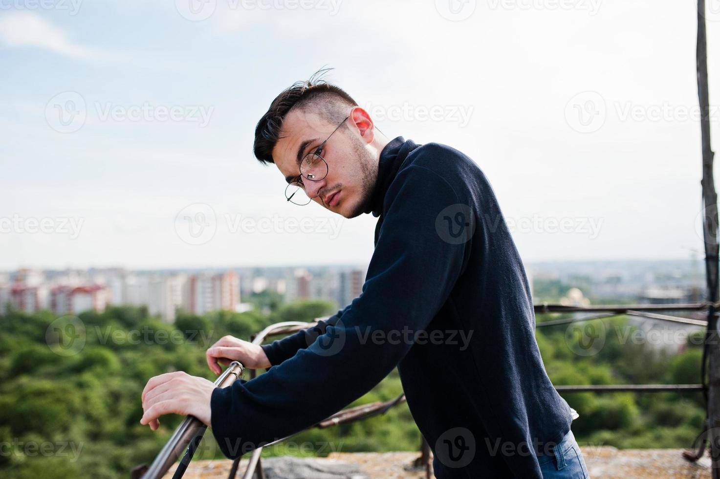 hombre macho con estilo soñador en golf negro y gafas posadas en el techo. foto