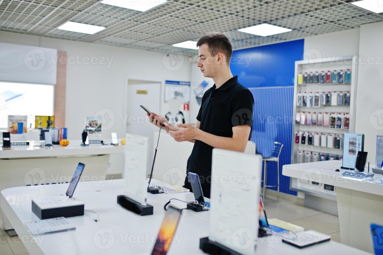 Seller man mobile phone professional consultant in tech store or shop hold new smartphone at  hand. photo