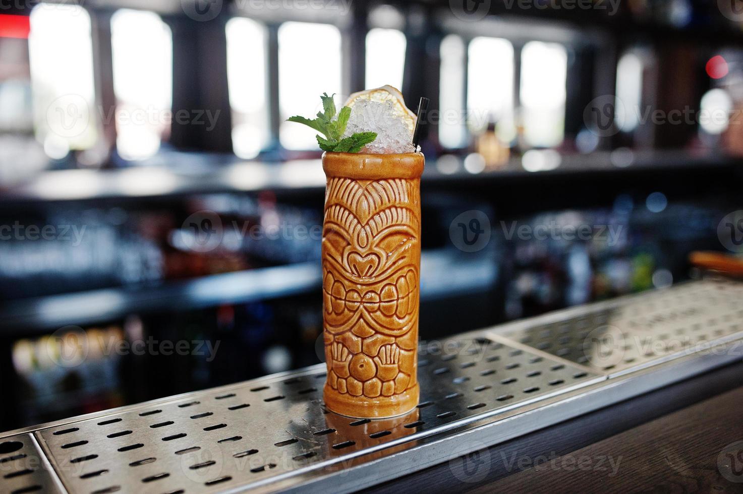 Alcoholic cocktail with mint in originally voodoo earthen glass on bar table. photo