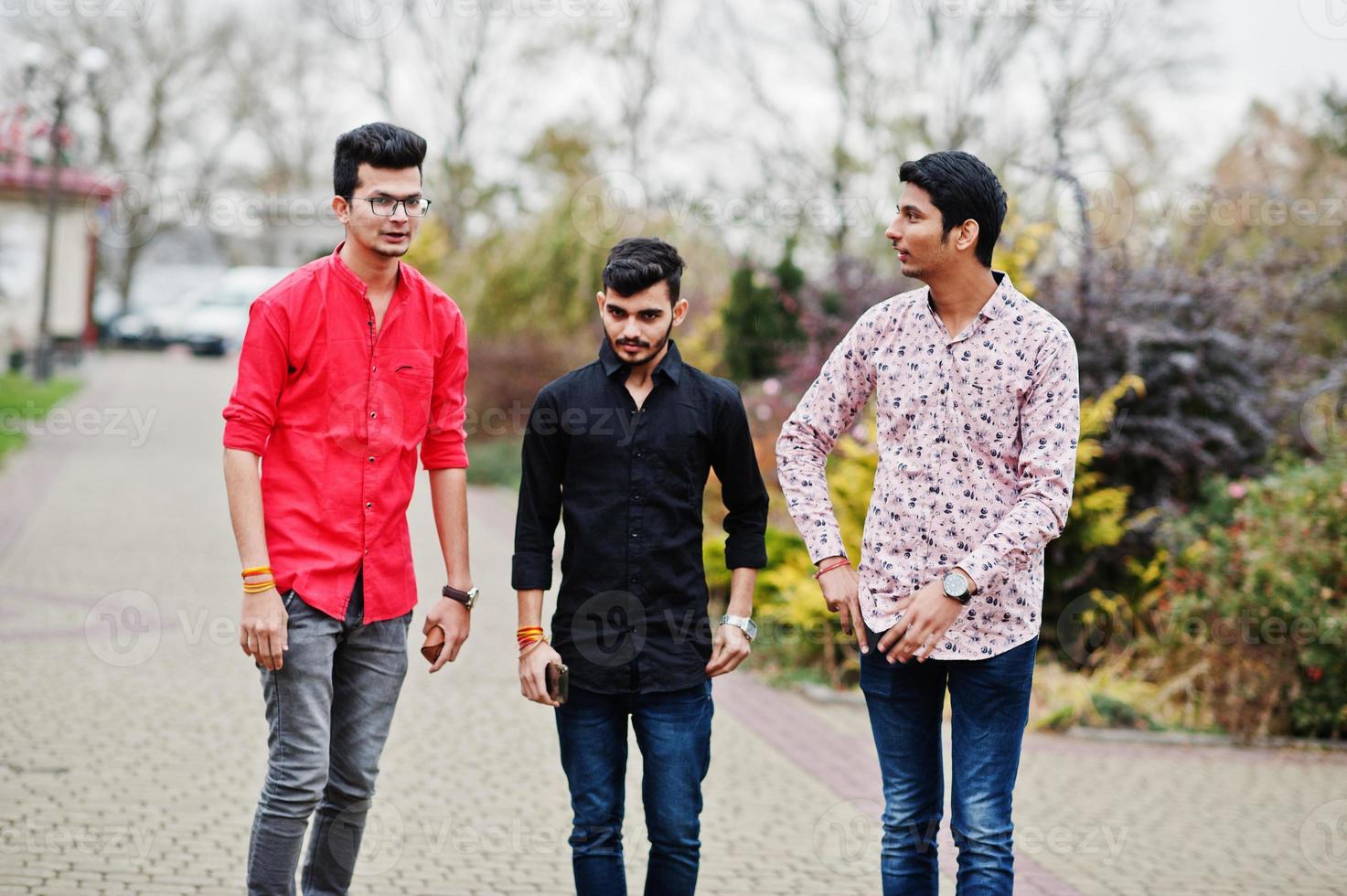 Three indian guys students friends walking on street. photo