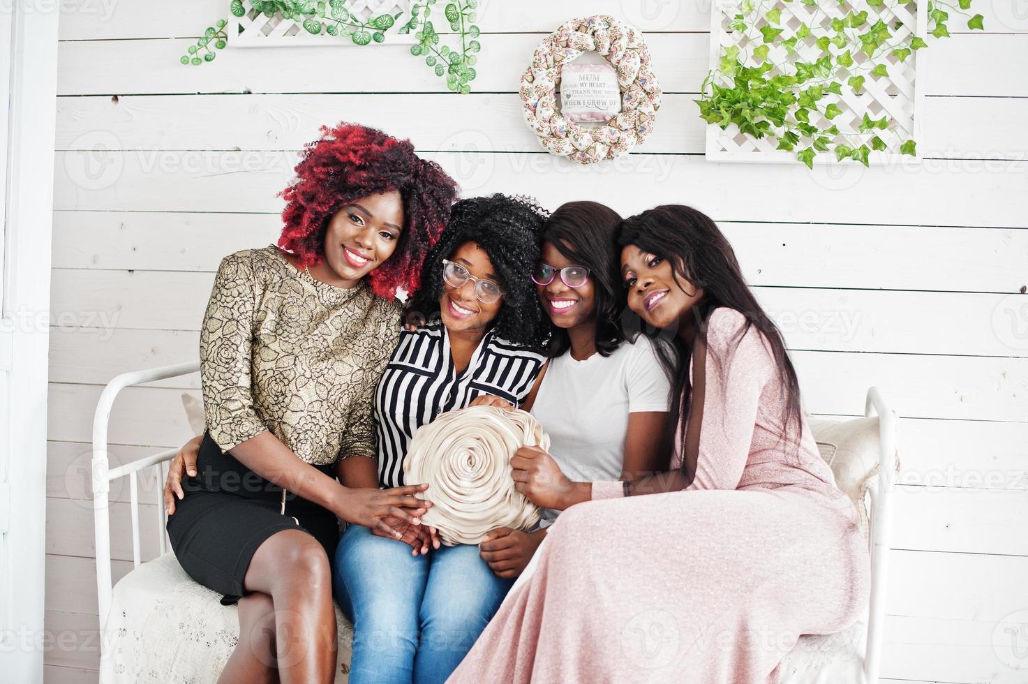 Four best friends. Young adrican women having fun, sitting on the retro couch. photo