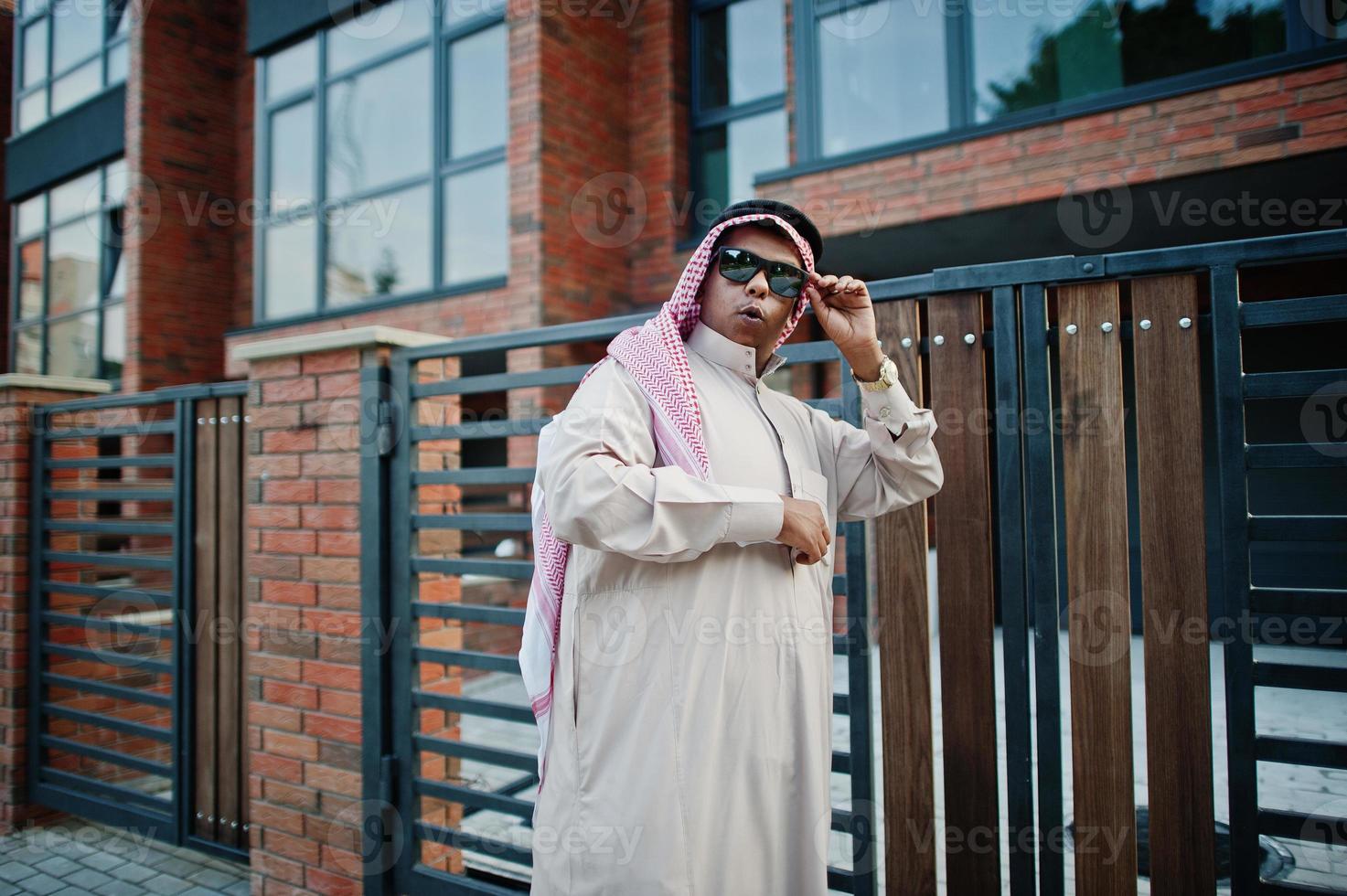 Middle Eastern arab business man posed on street against modern building with sunglasses. photo