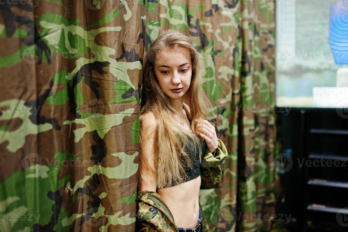 Military girl in camouflage uniform against army background. photo