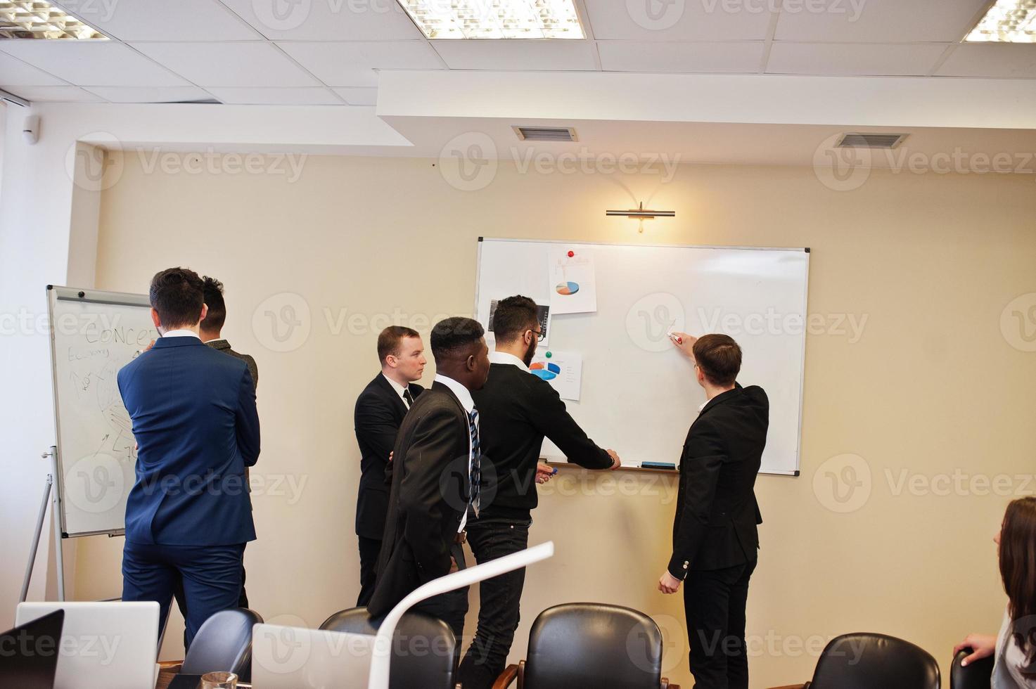 Male colleagues working in team cooperate , multiracial crew of employees concentrated on project planning against flipchart board and discussing ideas. photo
