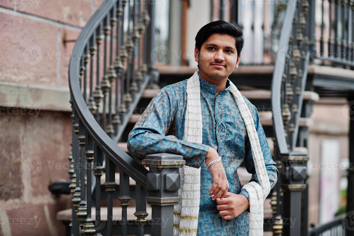 Indian man wear on traditional clothes with white scarf posed outdoor against iron stairs. photo