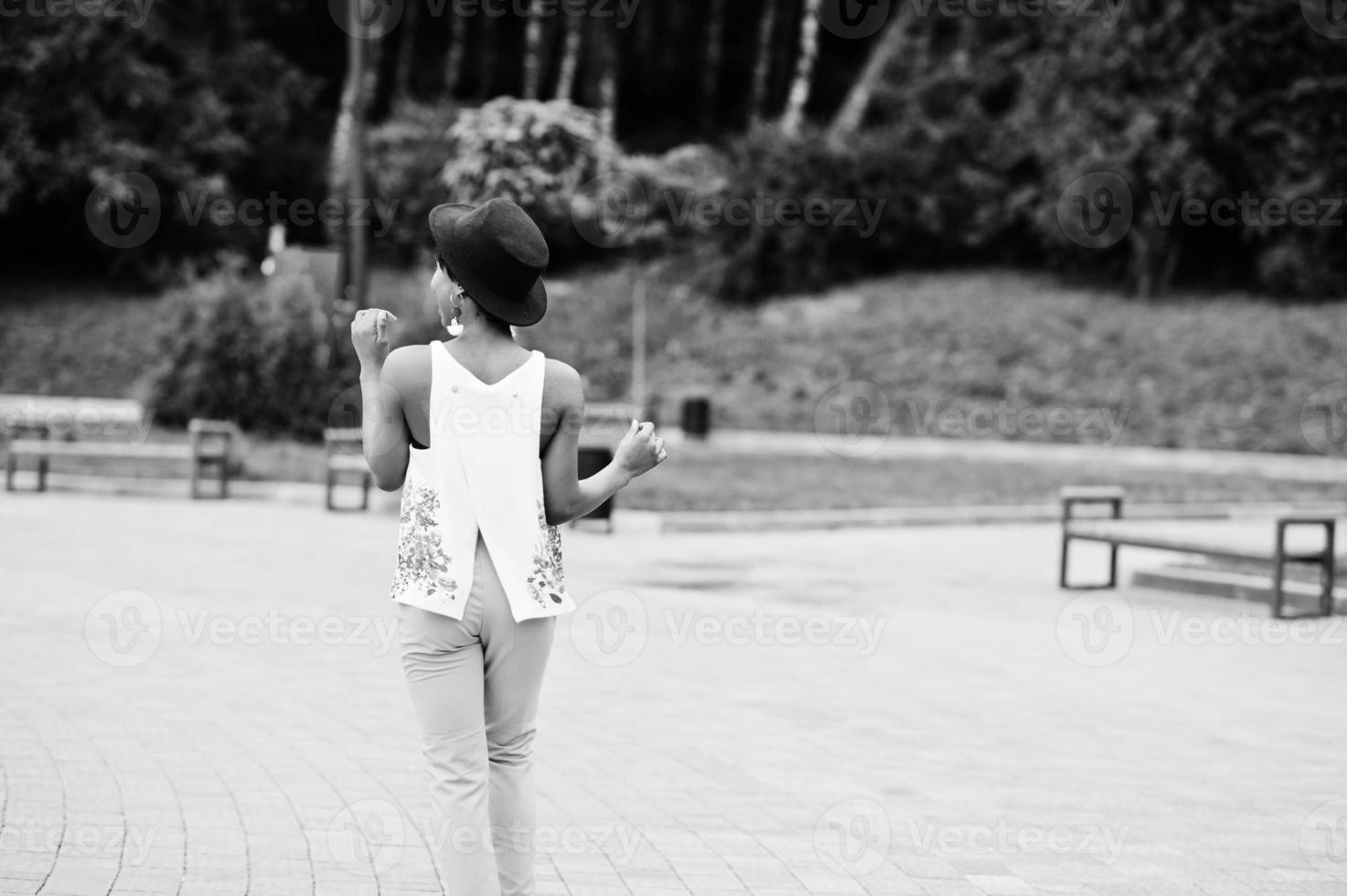 increíble mujer modelo afroamericana en pantalones verdes y sombrero negro posó en el parque. foto