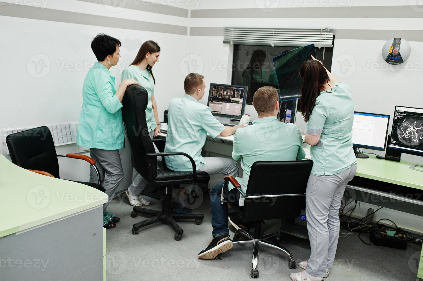 Medical theme.Observation room with a computer tomograph. The group of doctors meeting in the mri office at diagnostic center in hospital. Hold x-ray radiographic image. photo