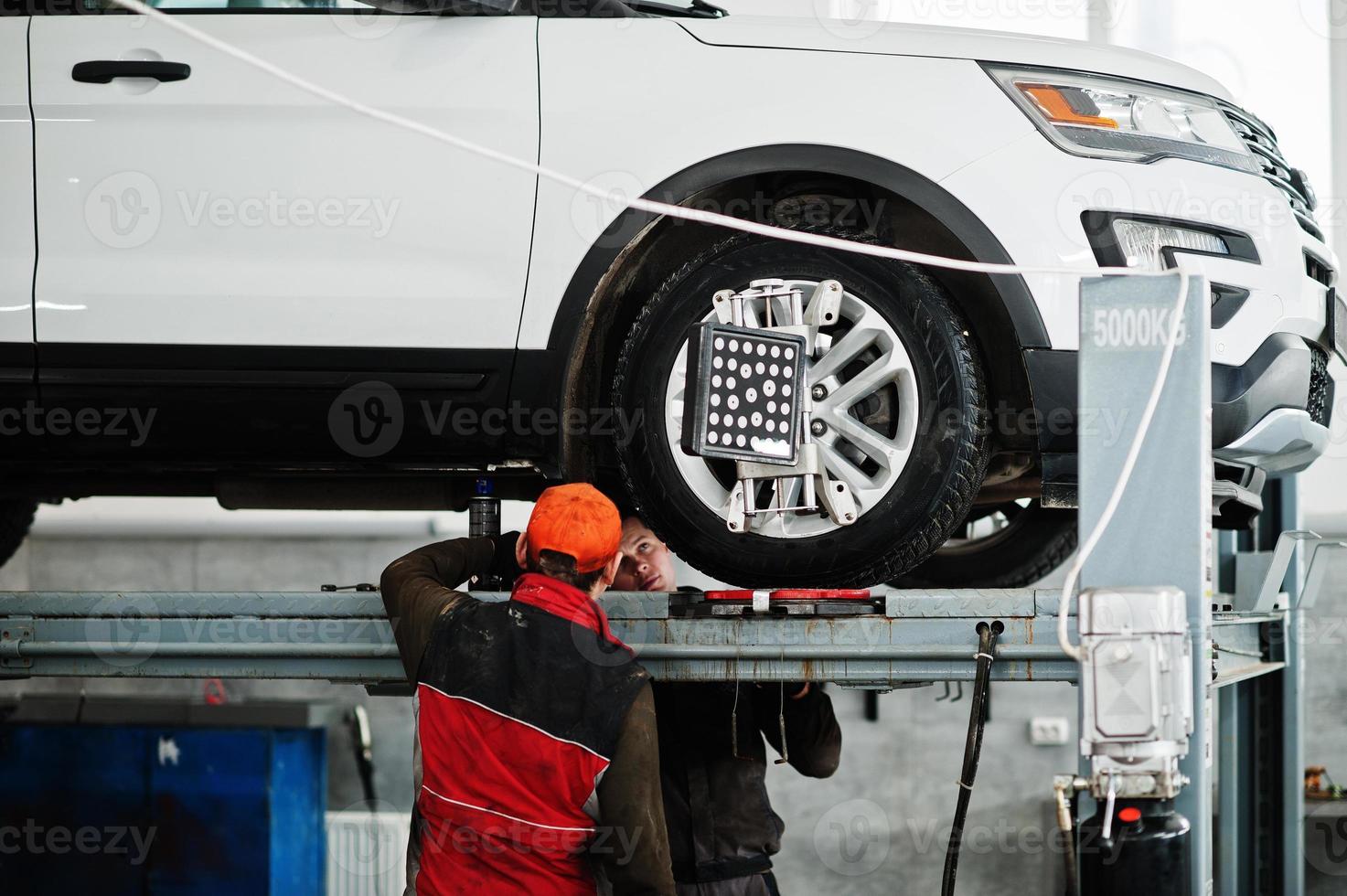 American SUV car on stand for wheels alignment camber check in workshop of service station. photo