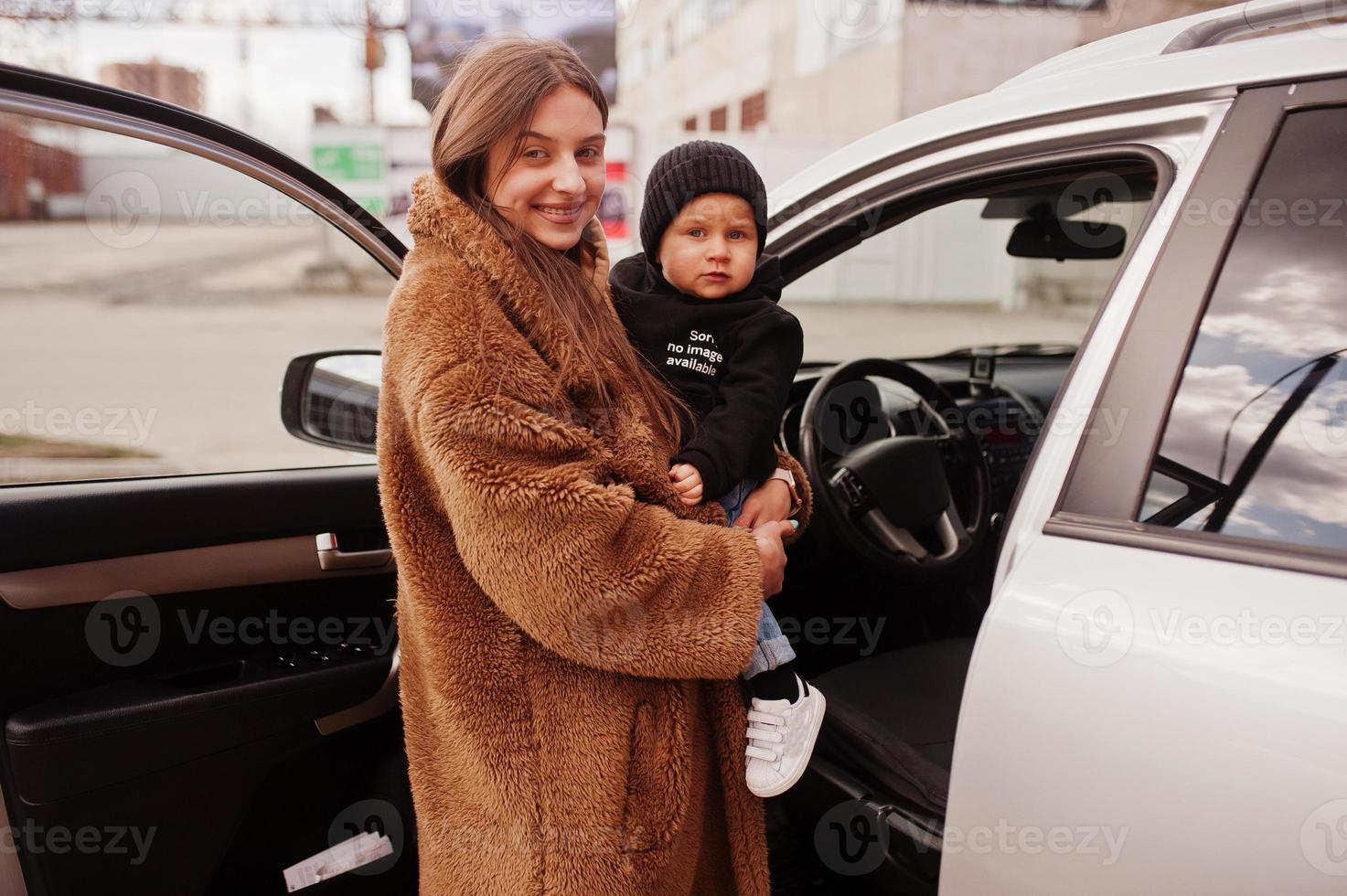 la joven madre y el niño se paran cerca de su auto todoterreno. concepto de conducción segura. foto