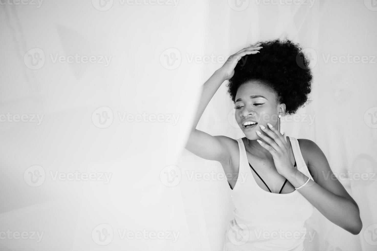 Young african american woman in pink singlet against window touching tulle. Perfect morning. photo