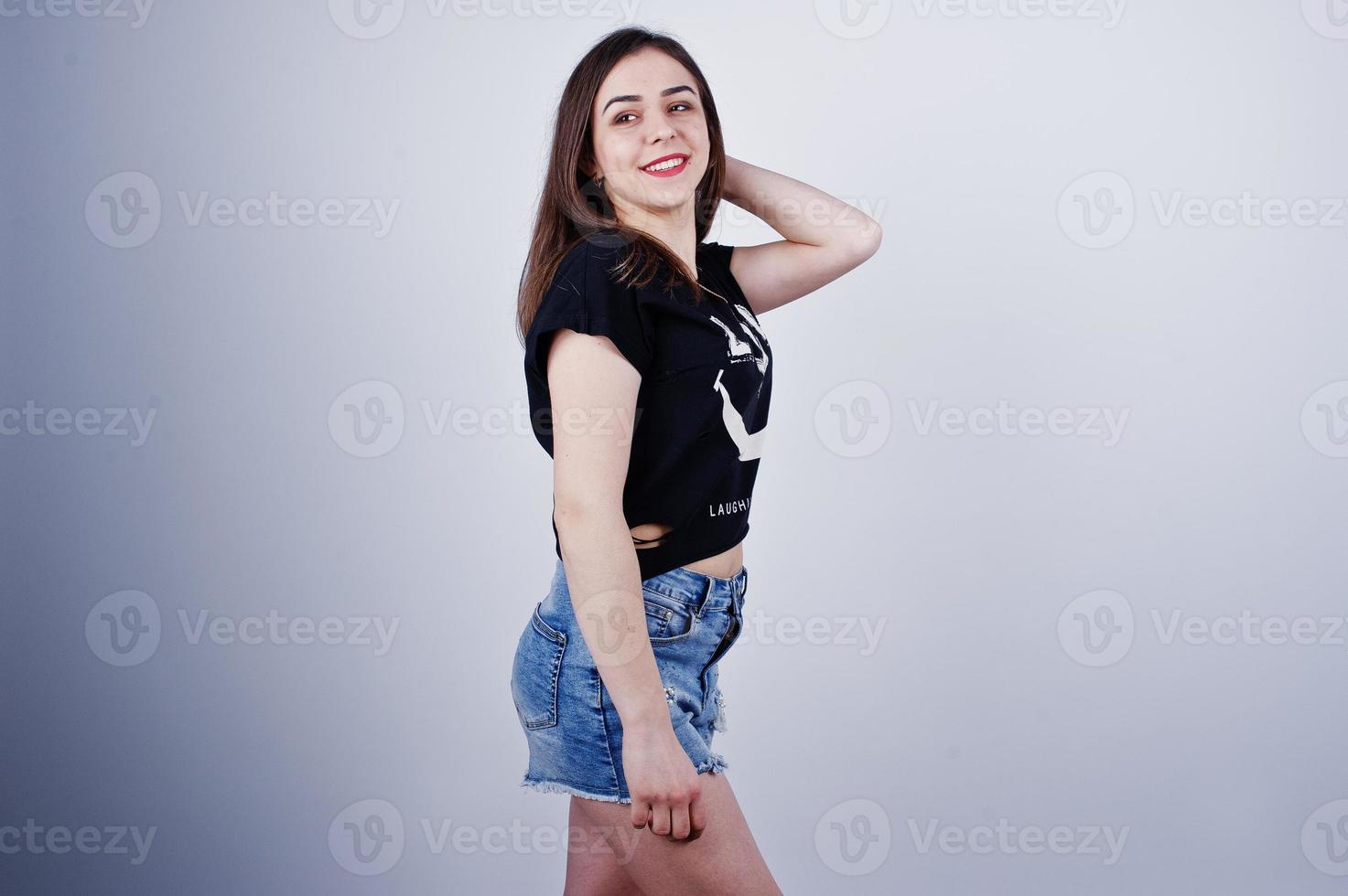 retrato de una chica atractiva en camiseta negra diciendo jajaja y pantalones cortos de mezclilla posando en el estudio. foto