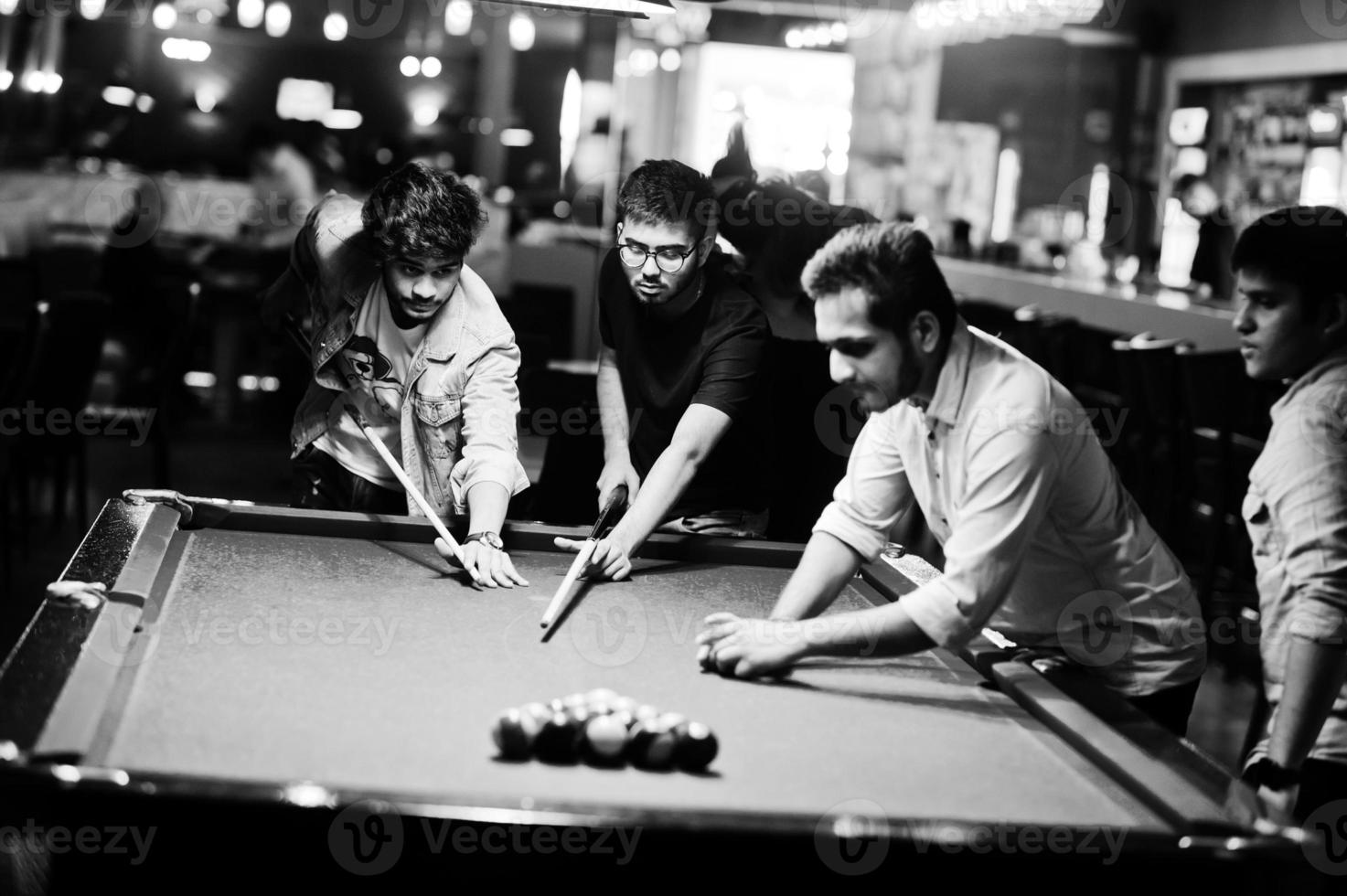 grupo de elegantes amigos asiáticos usan jeans jugando al billar en el bar. foto