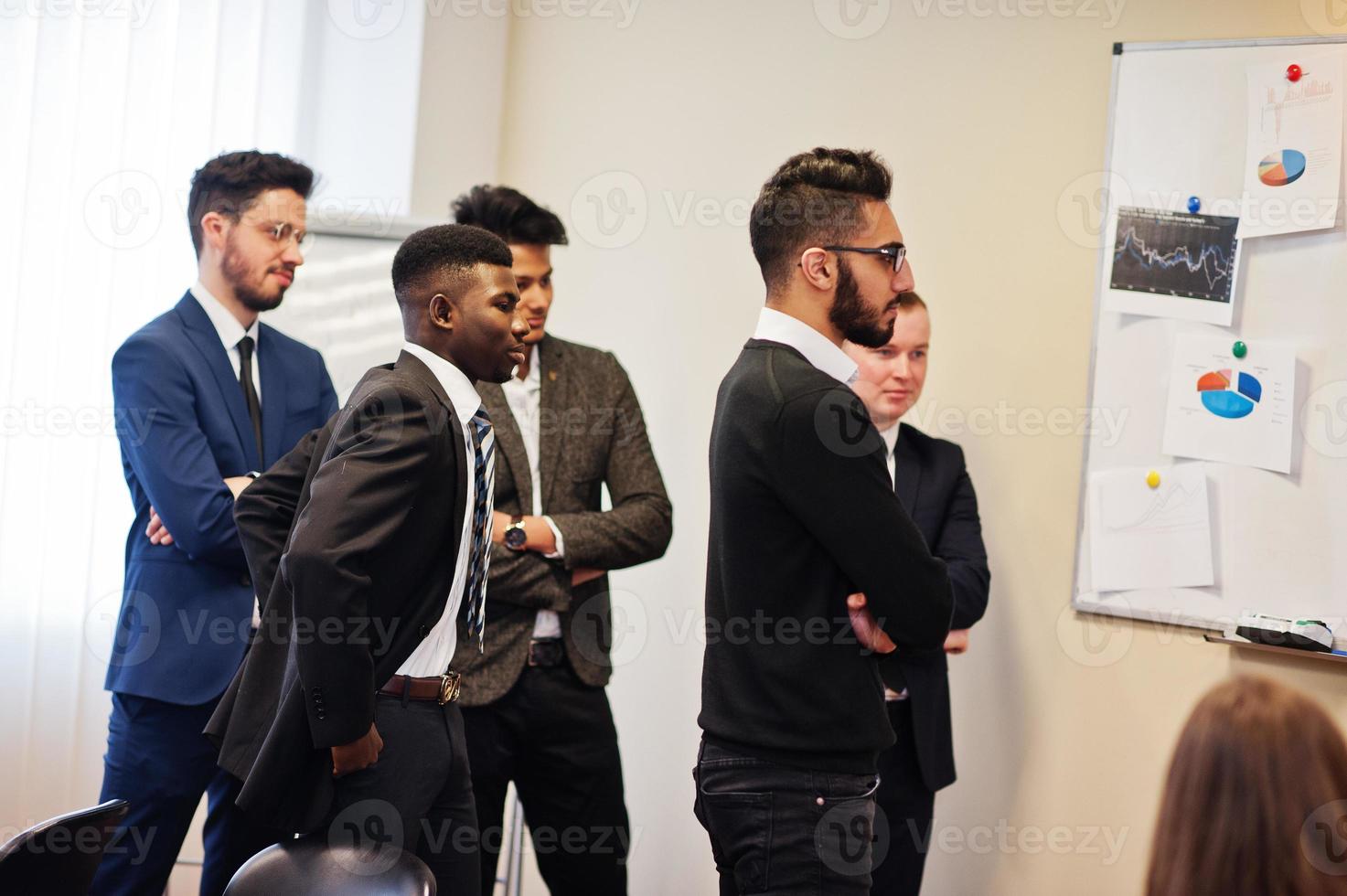 Male colleagues working in team cooperate , multiracial crew of employees concentrated on project planning against board and discussing ideas. photo