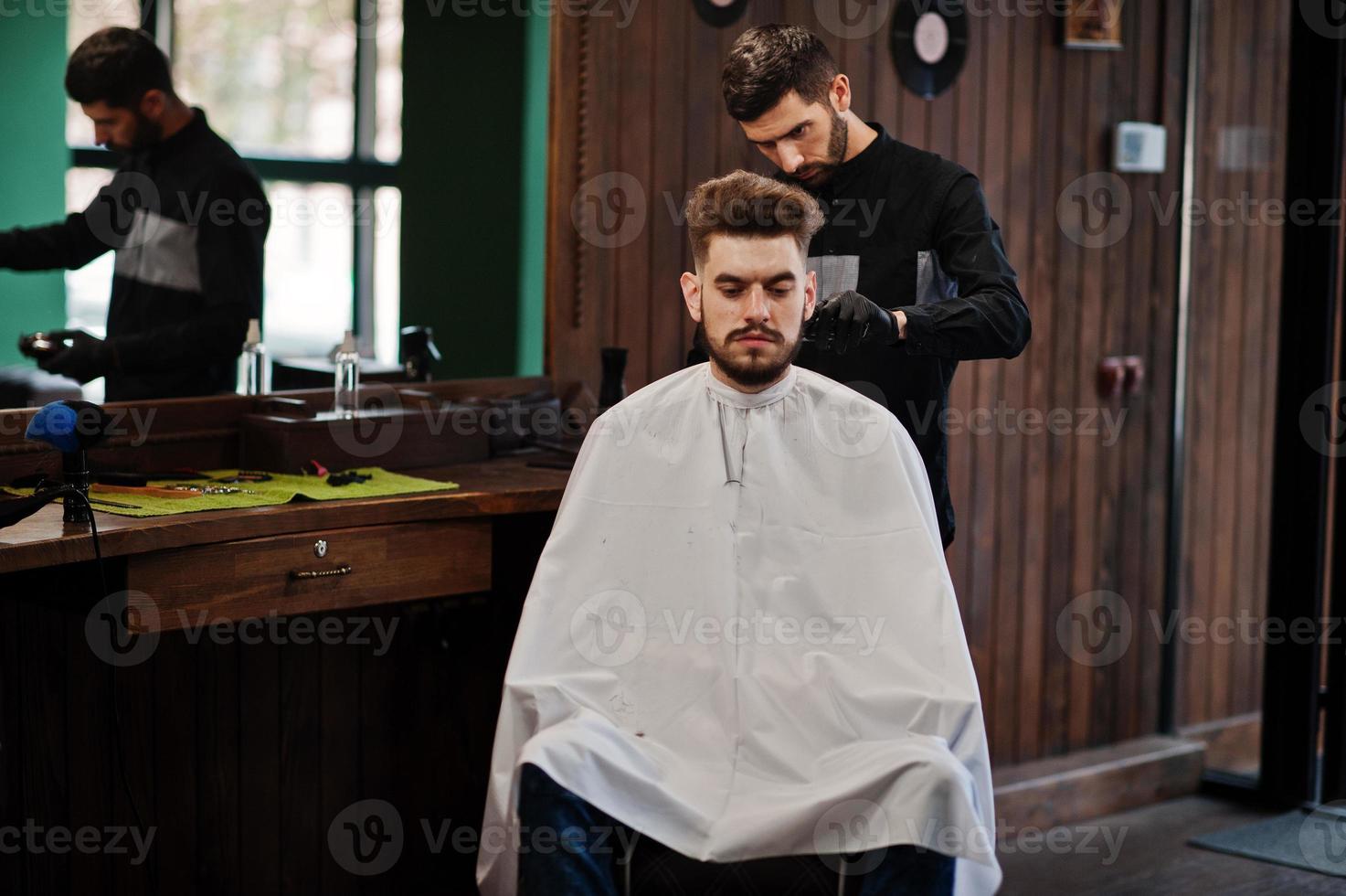 apuesto hombre barbudo en la barbería, peluquero en el trabajo. foto