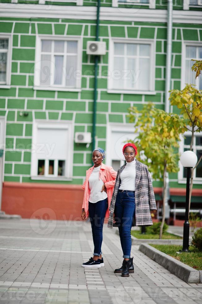 Two young modern fashionable, attractive, tall and slim african muslim womans in hijab or turban head scarf and coat posed. photo