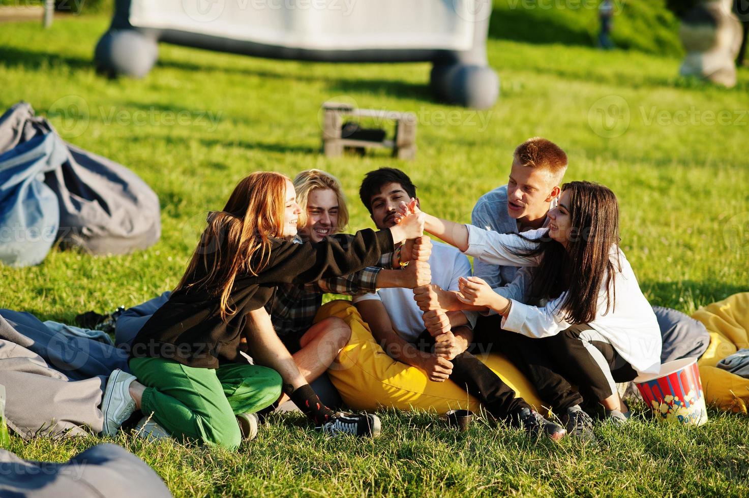 joven grupo multiétnico de personas viendo películas en poof en cine al aire libre. foto