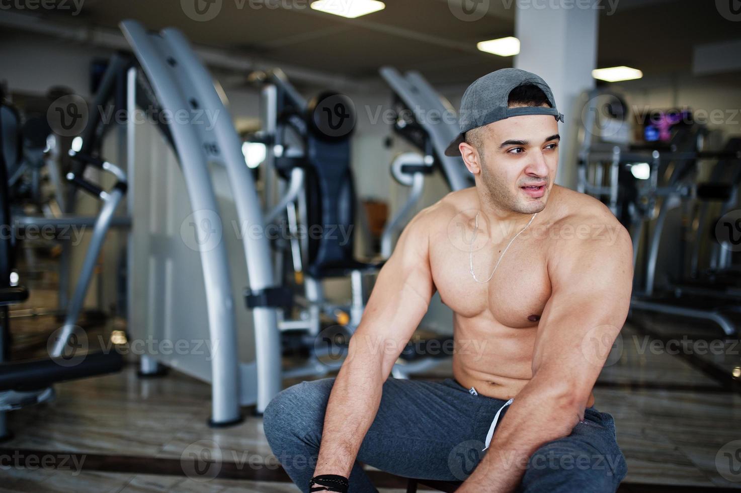 Fit and muscular arabian man doing workouts in gym. photo