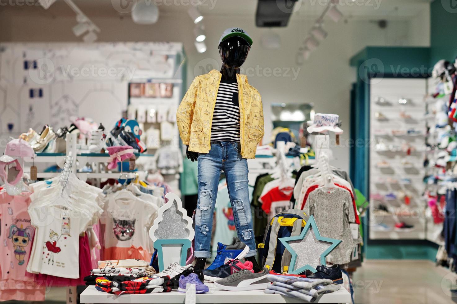 Children's bright clothes hang on the display in the baby clothing store with mannequin. photo