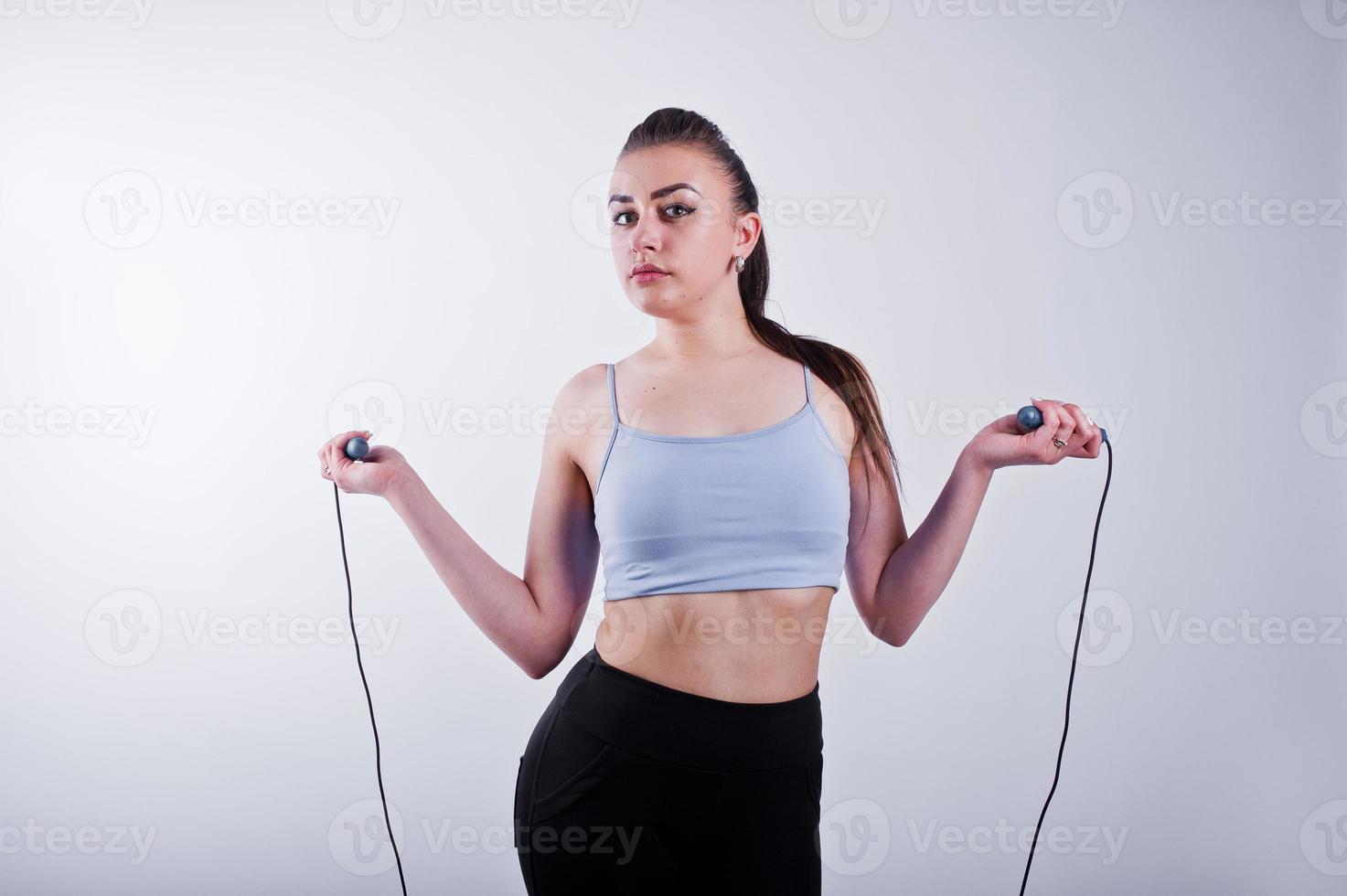 Cheerful attractive young fitness woman in top and black leggings with jump rope isolated over white background. photo