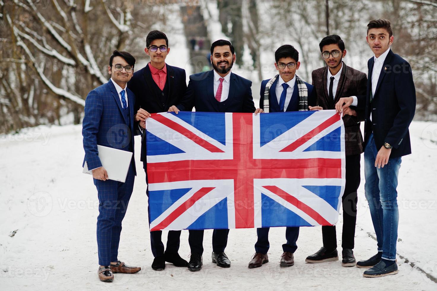 Group of six indian businessman in suits posed outdoor in winter day at Europe with flag of Great Britain. Friendly relations with India and UK. photo