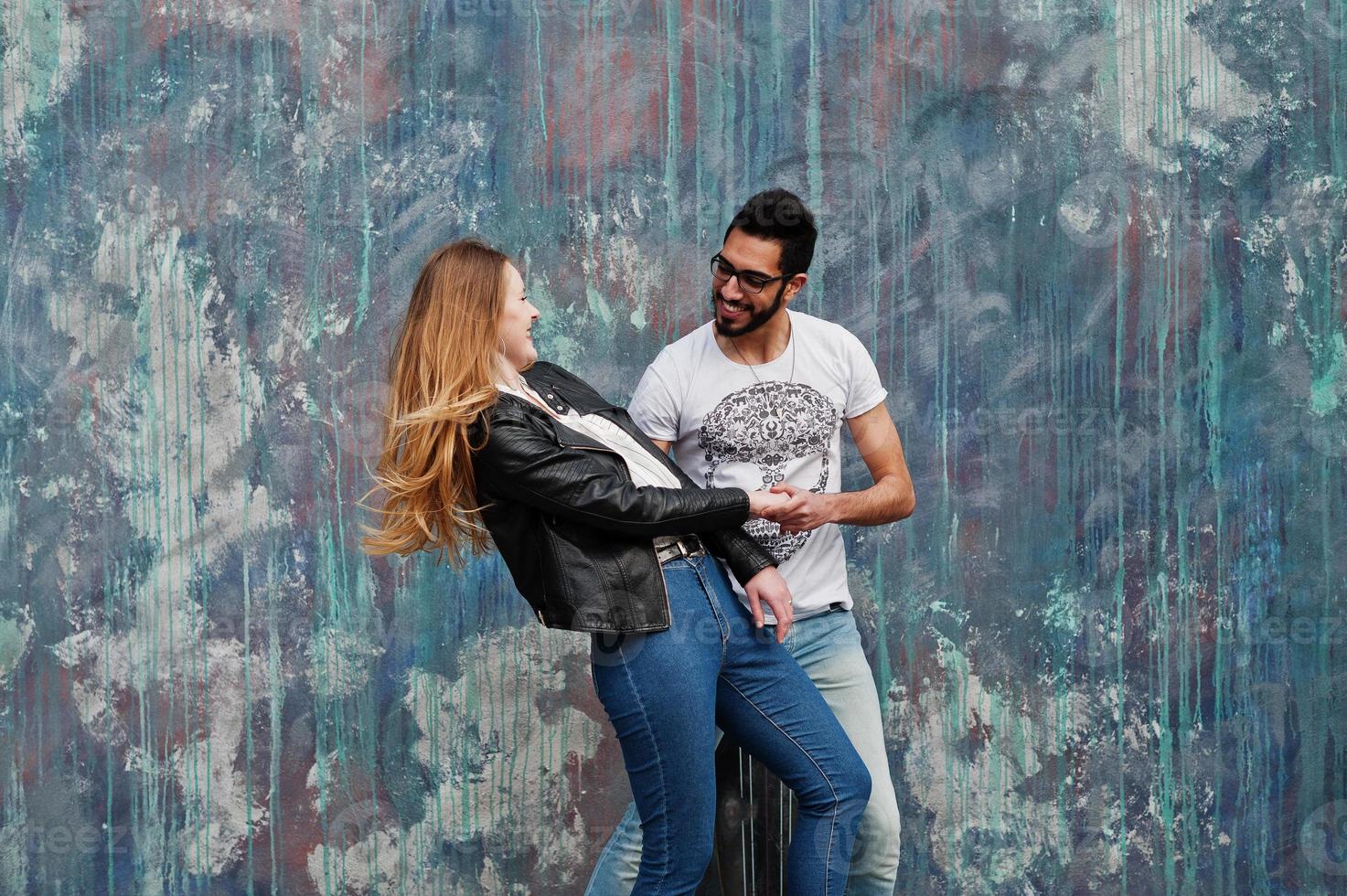 genial pareja multirracial posando contra la pared y bailando. foto