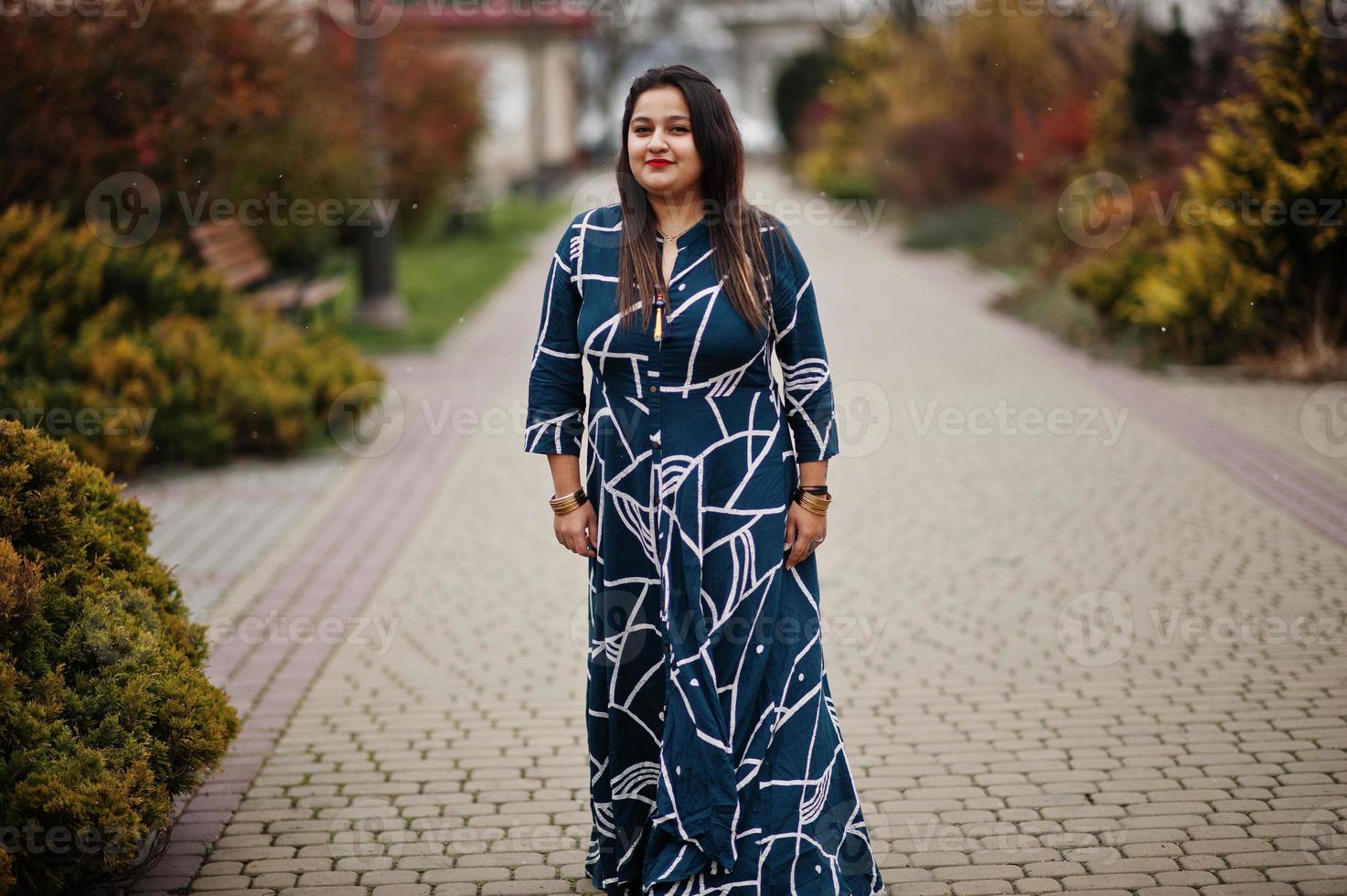 Brunette indian woman in long fashionable dress posed outdoor. photo