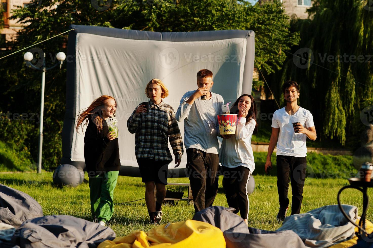 Young multi ethnic group of people watching movie at poof in open air cinema. photo